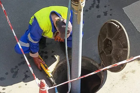 Technician cleaning a catch basin with a vacuum hose