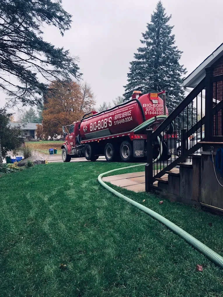 Bio-Bob's tanker at a residential driveway with the hose across the lawn