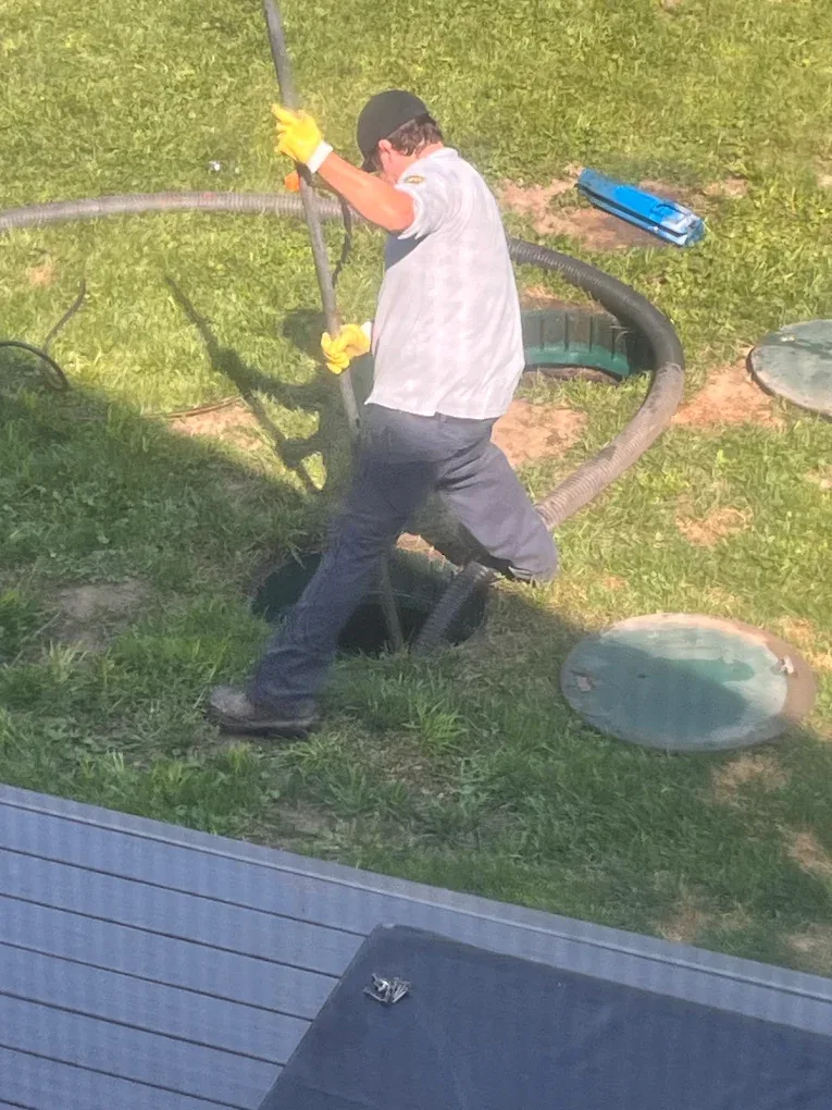 Bio-Bob's technician guiding the vacuum hose into an open septic tank